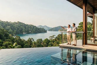 Couple sur la terrasse d'une villa de luxe en Thaïlande avec vue sur une baie turquoise, illustrant le marché immobilier thaïlandais